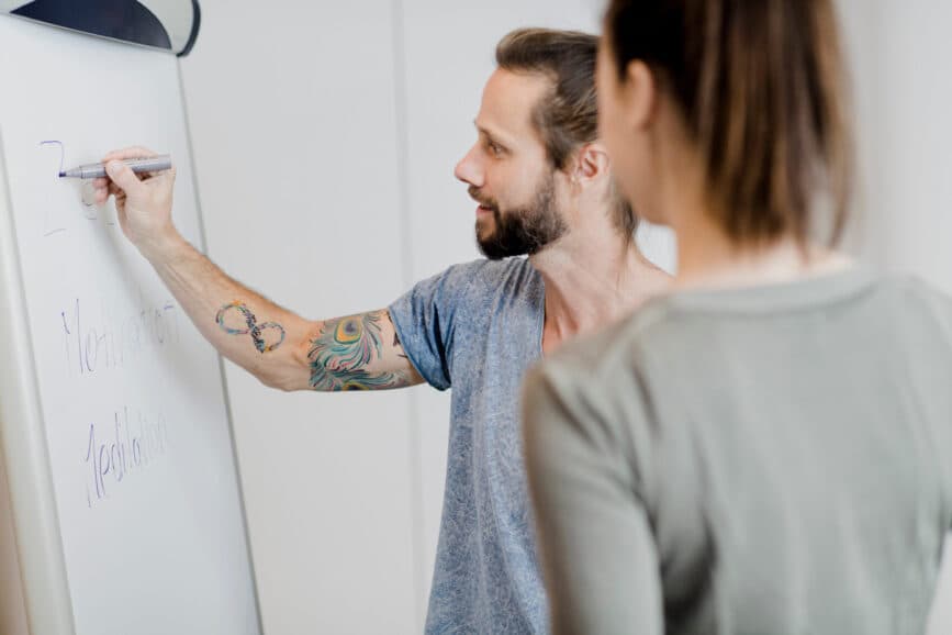 Symbolbild zwei Personen die an einem Whiteboard zusammenarbeiten